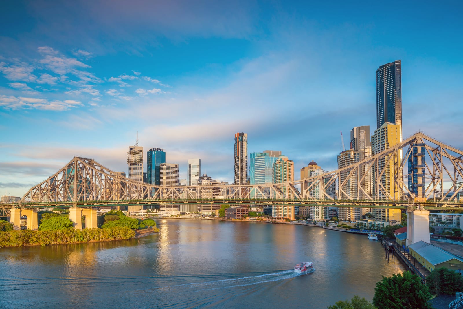 The Story Bridge and Brisbane CBD towers above the Brisbane River in warm late-afternoon light